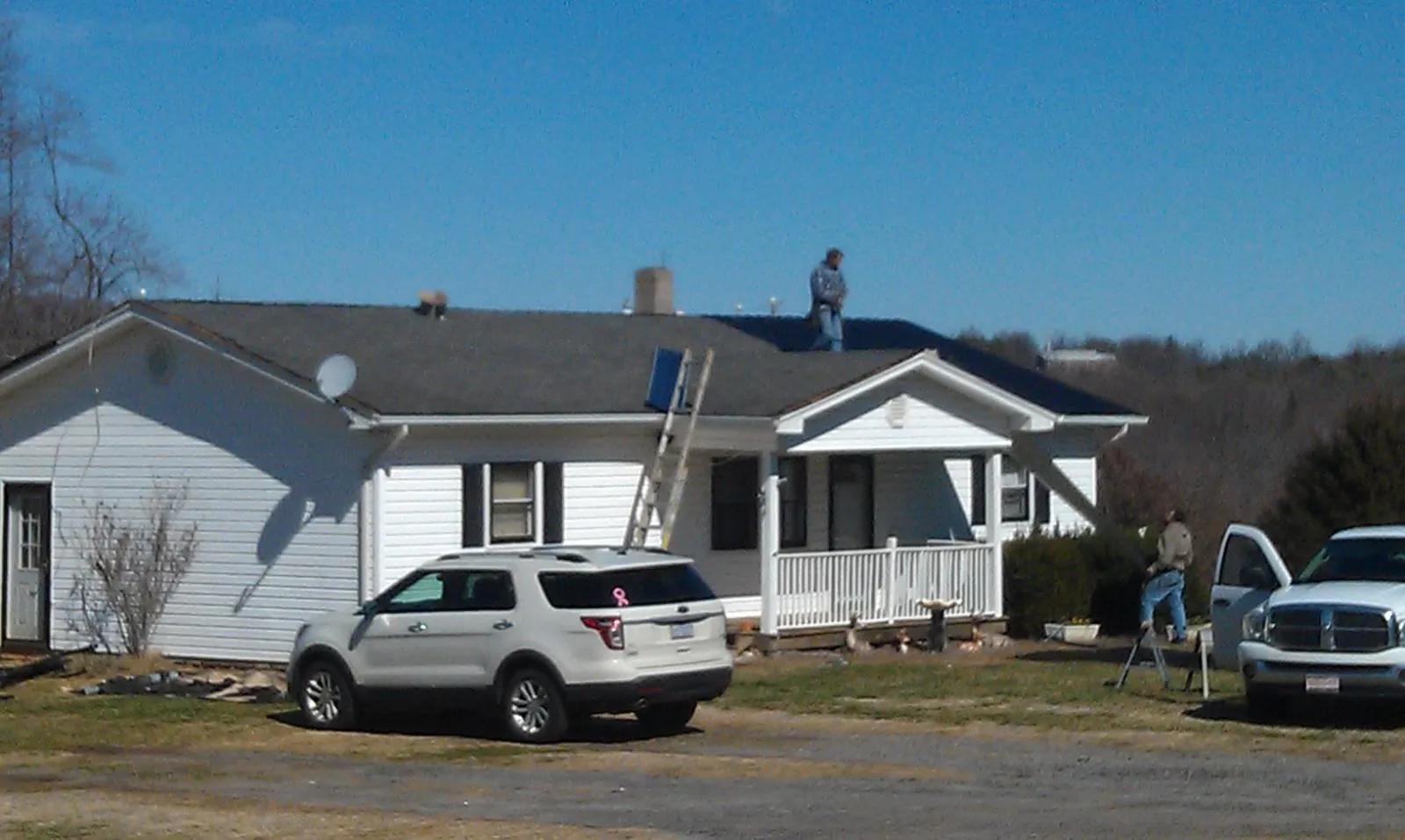 Roofers stripping shingles from a white ranch house roof in Franklin